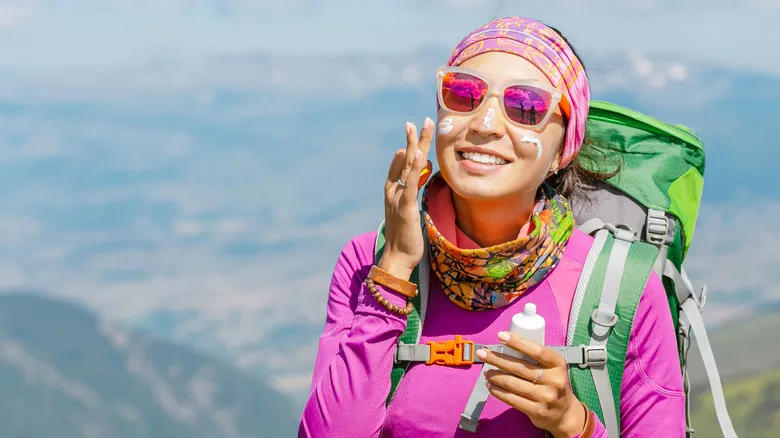 Hiker putting sunscreen lotion on her face