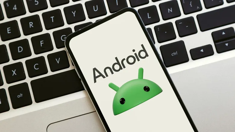 Android logo on a smartphone with laptop keyboard in the background