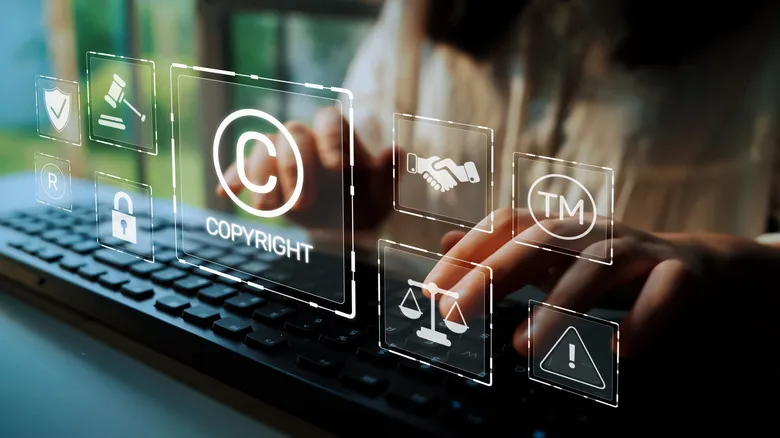 the copyright symbol in holographic form hovering over a person's hands on a keyboard