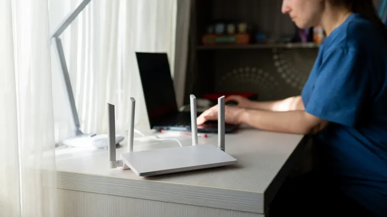 A person working at a desk next to a white router