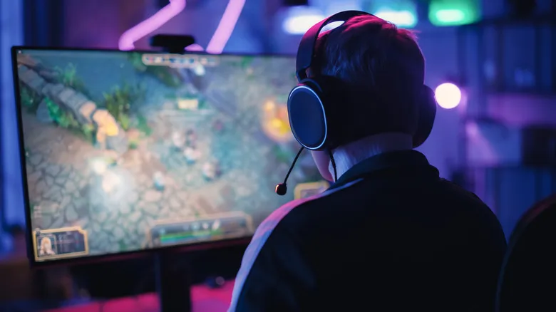 Person wearing headset playing a game on a desktop monitor.