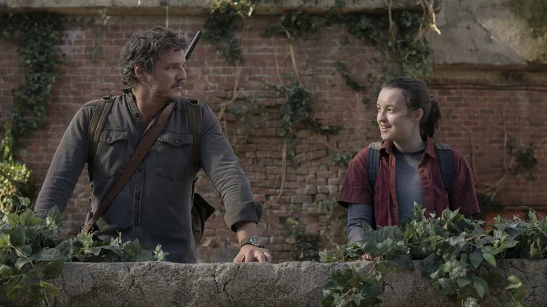 Joel and Ellie talking beside ivy-covered wall in The Last of Us (2023)