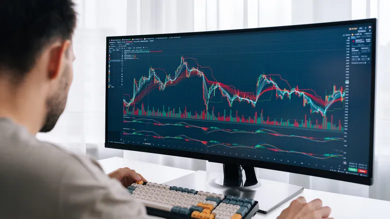 Person analyzing stock market charts on ultrawide monitor