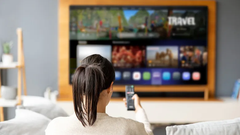 Person using a remote control to navigate a smart TV interface from a couch.