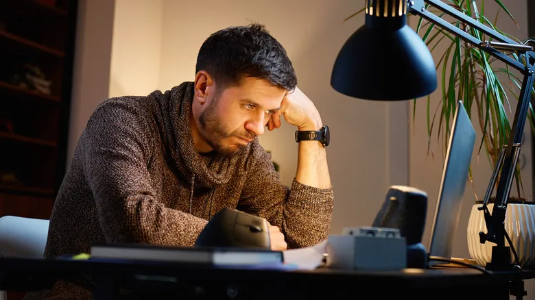 Person frustrated while working at laptop