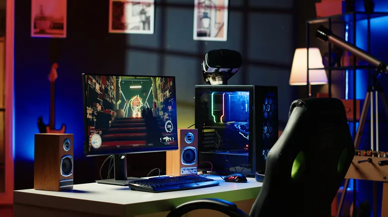 Gaming PC setup with monitor, RGB case, speakers, and VR headset on a desk.