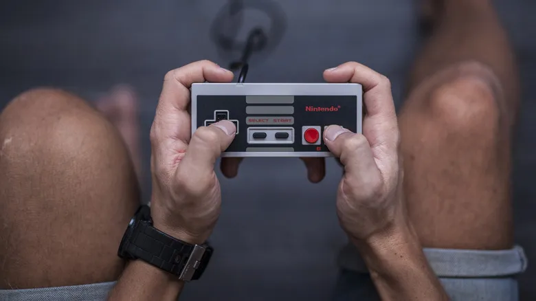 Close-up of hands holding a classic Nintendo-style game controller.