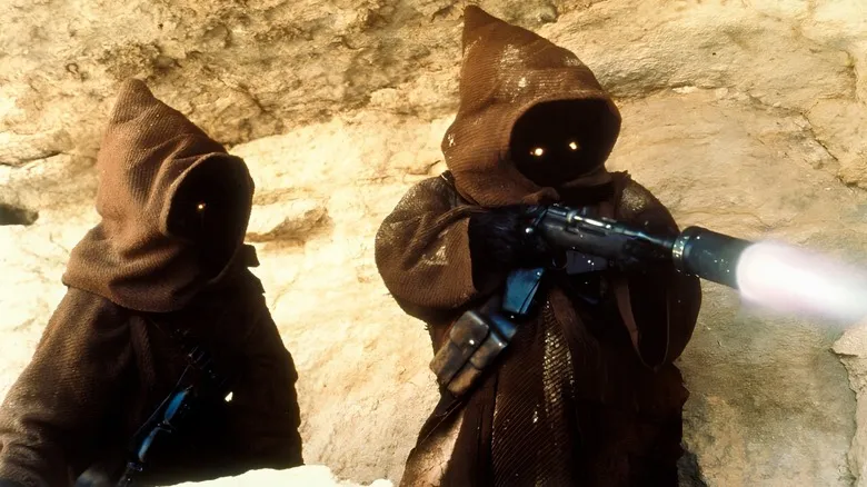 One Jawa watching another shoot a blaster on the desert planet of Tattooine.