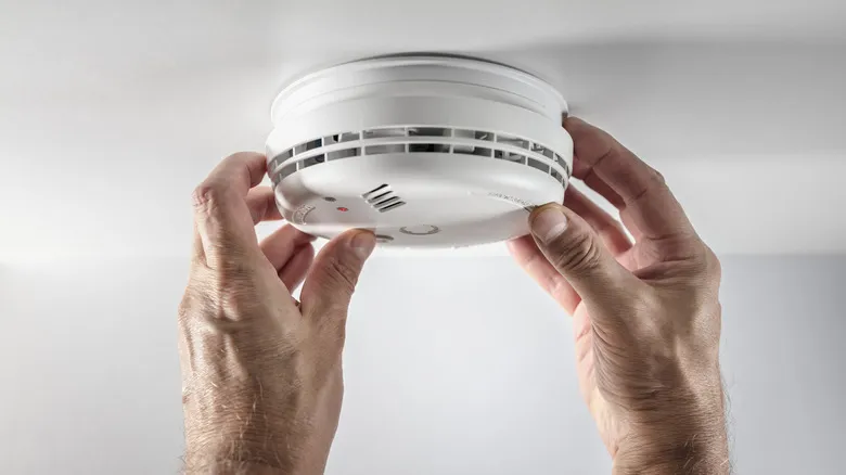 A person installing a home smoke detector.