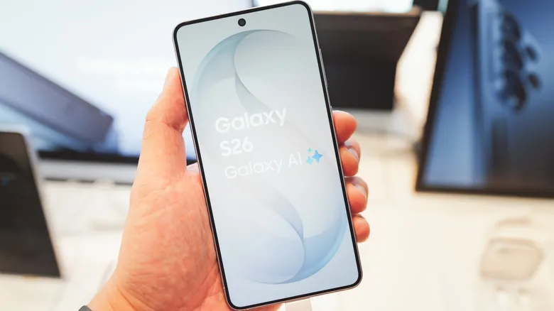 A person holding a Galaxy S26 in their hand showing the phone display on its screen the logo and Galaxy AI on it