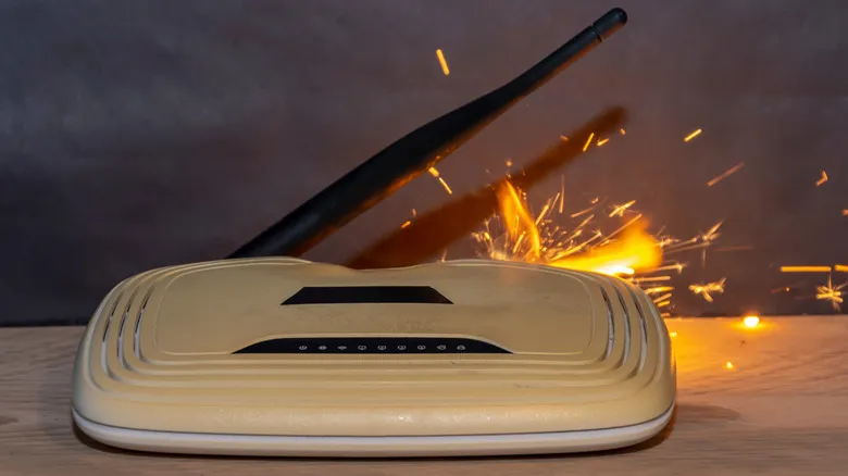 A white wi-fi router placed on a wooden table catches fire from overheating
