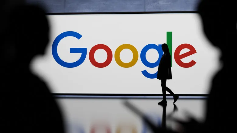 A Google logo on a billboard, with a person walking in front of it