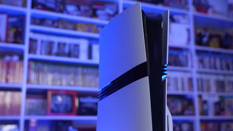 The base PlayStation 5 bathed in blue light with blurred bookshelves of games in the background.