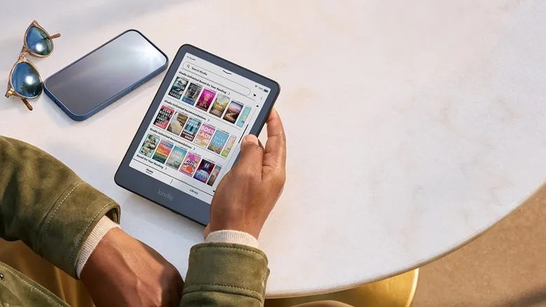 Person browsing a Kindle's ebook library while sitting at a table