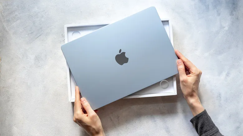 Person holding a MacBook out of the retail box.