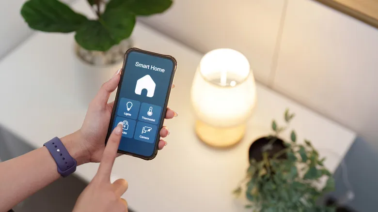 Person controlling smart home app on smartphone to adjust lights and temperature