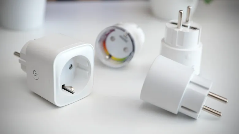 Smart plug and European power adapters placed on white surface