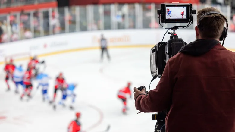 A camera man shooting a hockey game from the press box