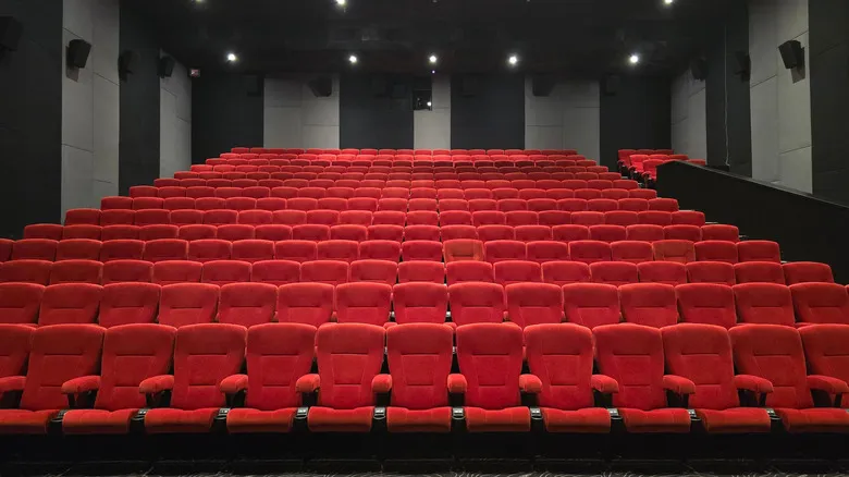 A cinema with rows of red seating and dark black and grey soundproofed walls