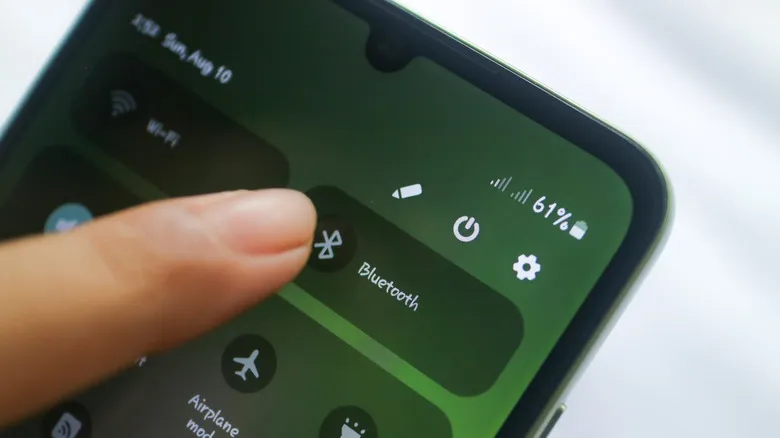 Finger about to tap the Bluetooth icon in the control panel of an Android smartphone